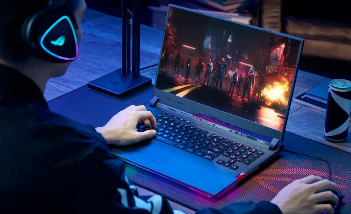 The back of a man playing games on a black laptop, displaying a mouse and keypad